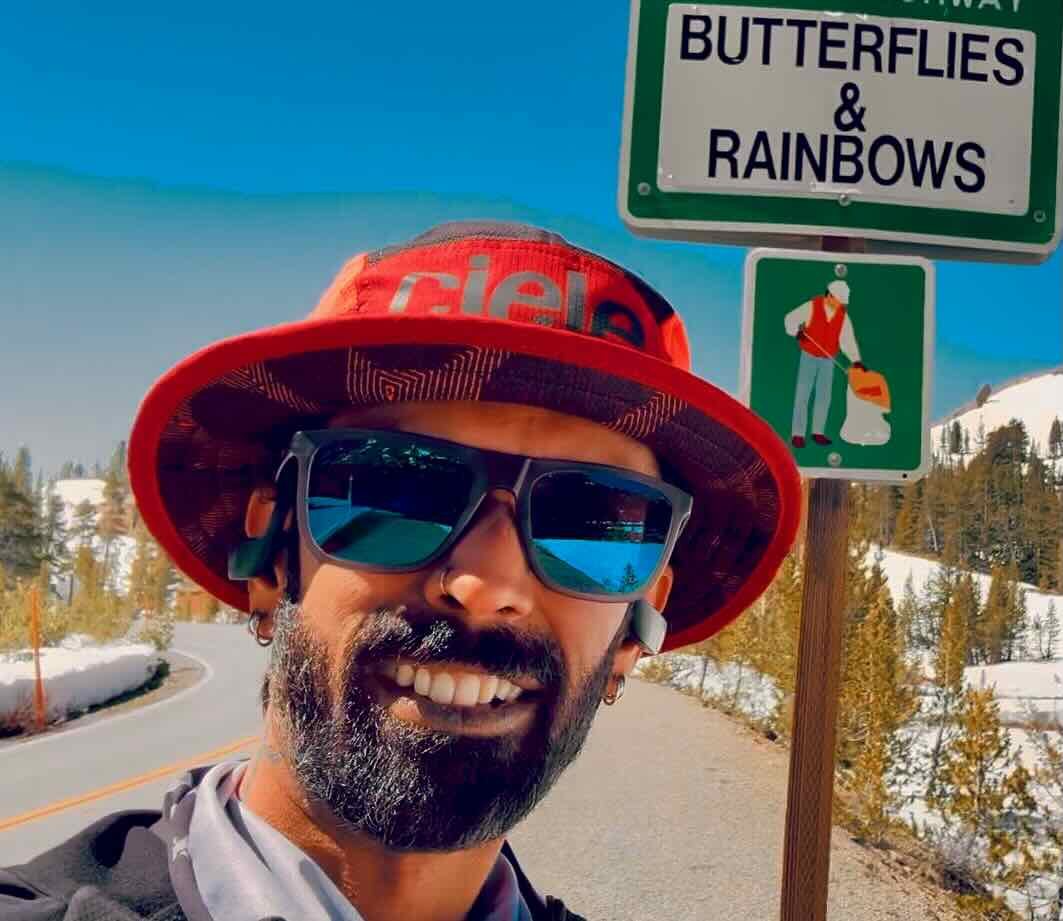 Anil running near a Butterflies and Rainbows sign on Tioga Pass